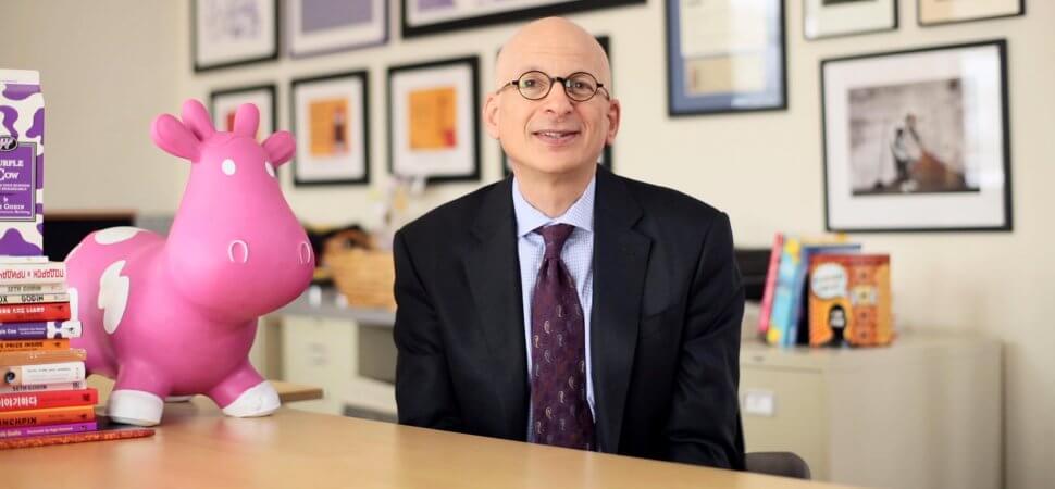 Seth Godin's image where he sits on his reading table with a unicorn and lots of books around him